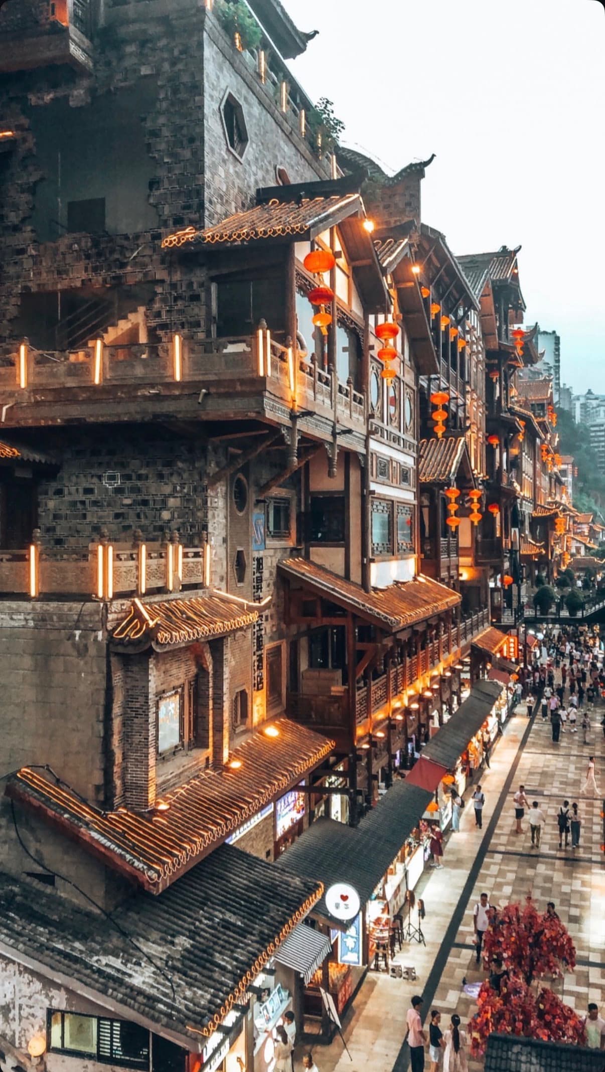 The Hongyadong stilt-house complex lit gold at night above the Jialing River in Chongqing