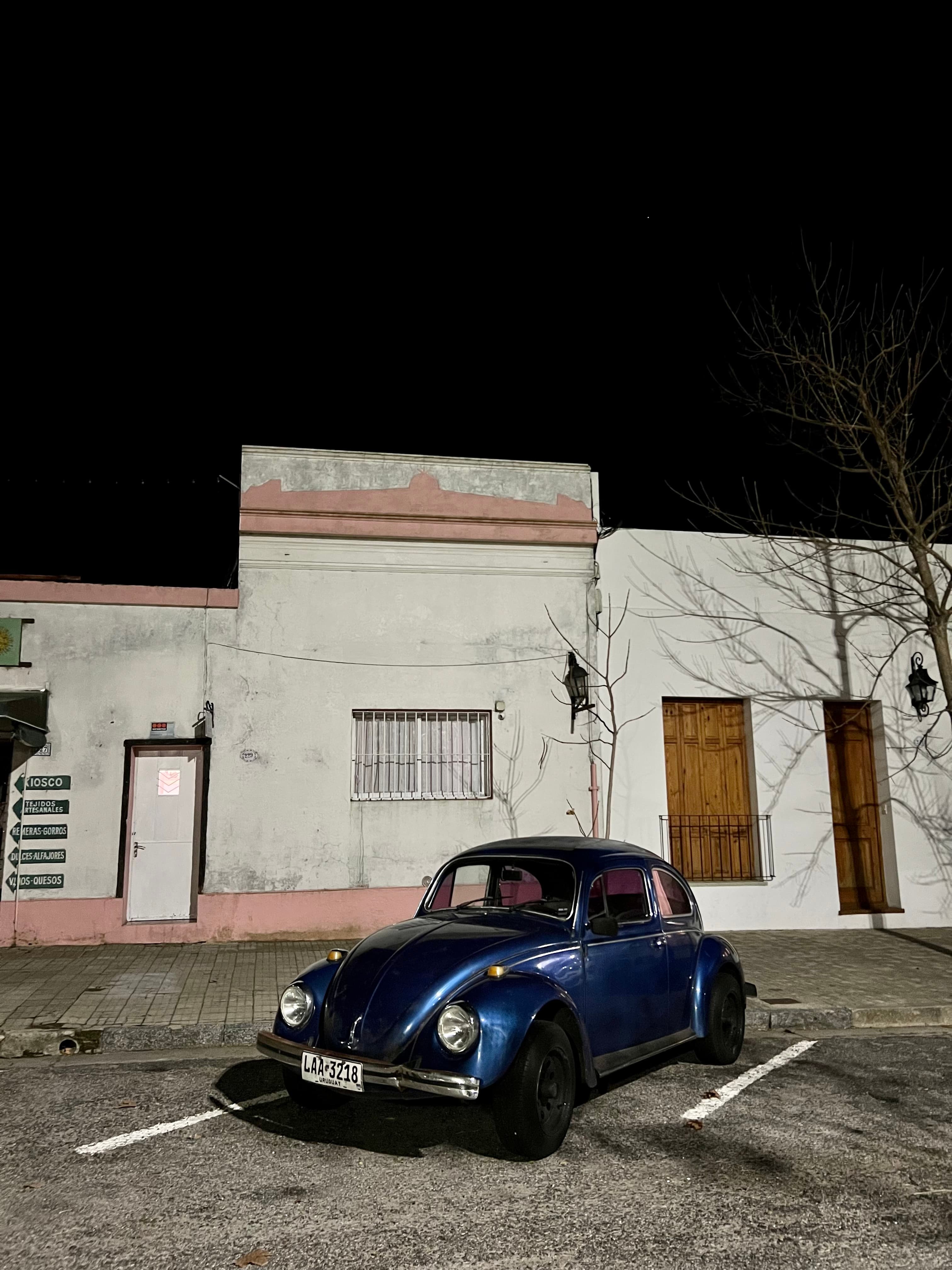 Vintage blue Volkswagen Beetle parked at night in front of a colonial house in Colonia del Sacramento