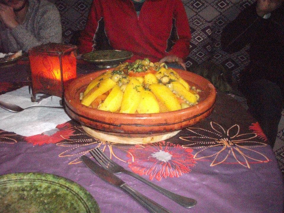 A vegetable tagine served in its earthenware dish by lantern light at the desert camp in Morocco