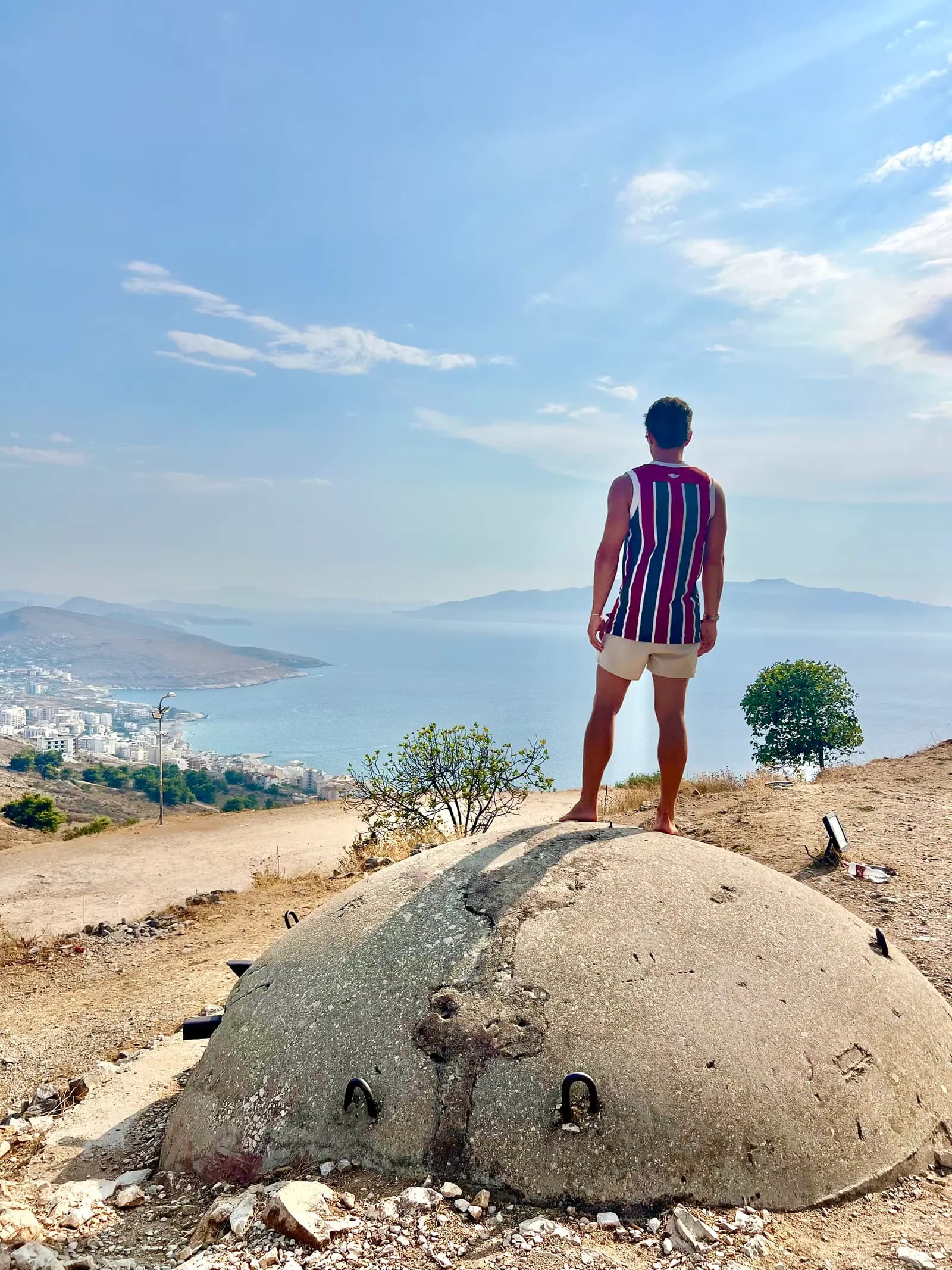 Traveler standing on an old hilltop bunker overlooking the Ionian coastline near Ksamil, Albania